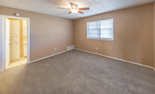 an empty room with windows and chandelier fan