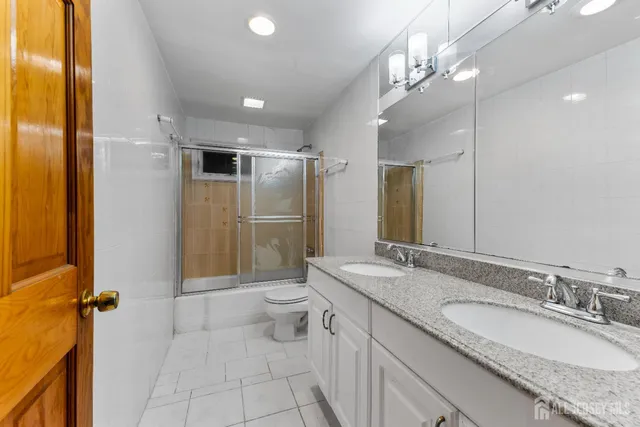 a bathroom with a granite countertop sink a toilet a mirror and shower