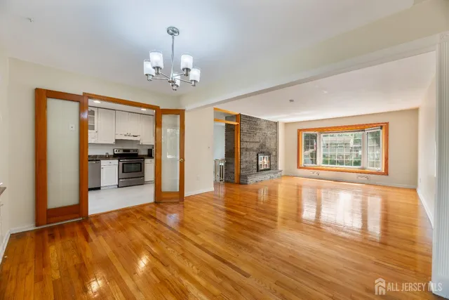 a view of an empty room with kitchen and a window