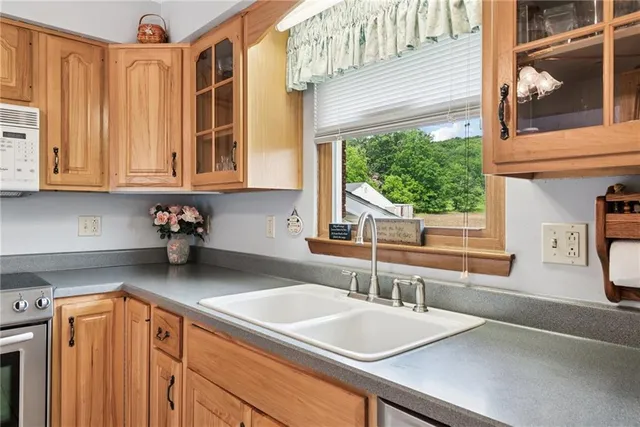 a kitchen with stainless steel appliances granite countertop a sink a stove and a wooden cabinets