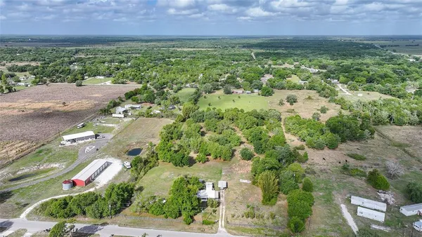 an aerial view of residential houses with outdoor space and trees