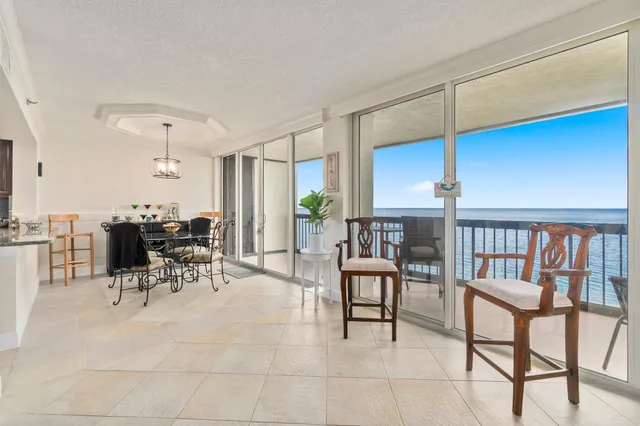a living room with furniture a dining table and a floor to ceiling window