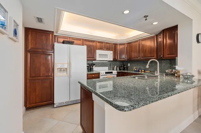 a kitchen with granite countertop a sink stainless steel appliances wooden cabinets and a counter top space