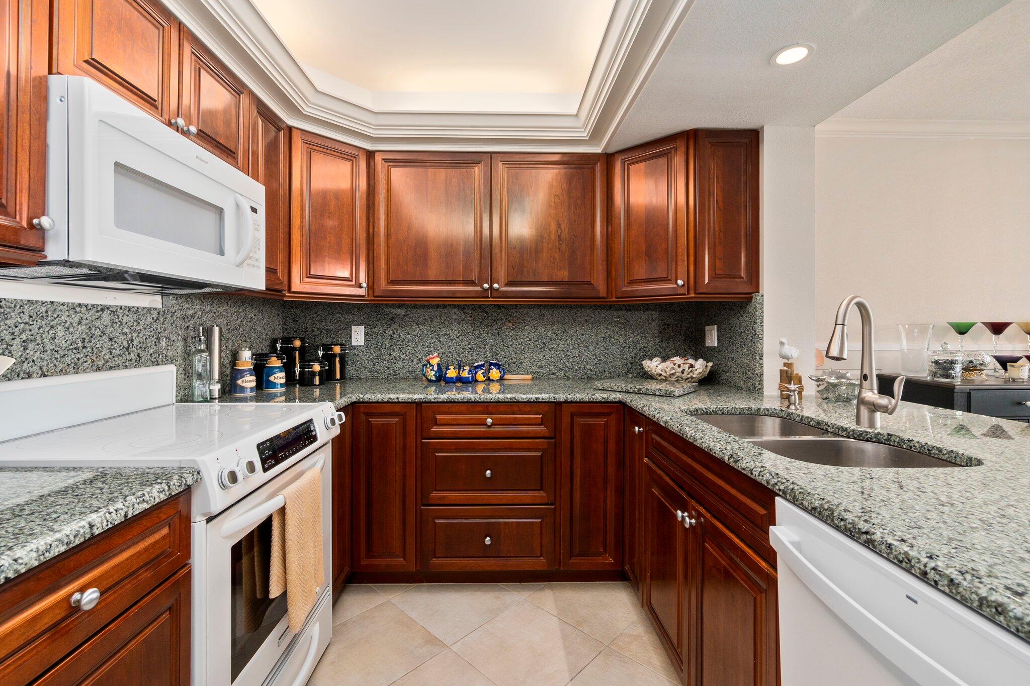 3100 North Hwy A1A, Unit PHA4 Fort Pierce, FL 34949 - Photo 18 of 54 a kitchen with granite countertop a sink stainless steel appliances wooden cabinets and a counter top space