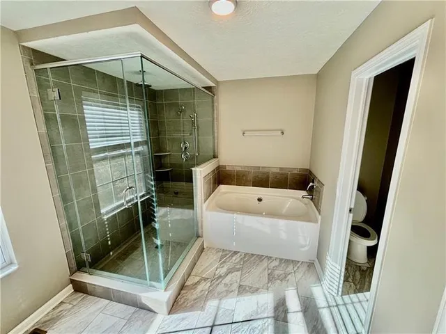 a bathroom with a tub a mirror and a shower