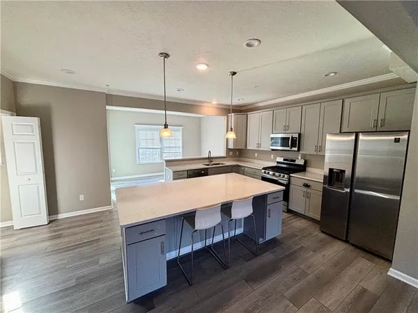a large kitchen with kitchen island a large counter top space a sink stainless steel appliances and cabinets