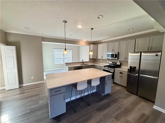 a large kitchen with kitchen island a large counter top space a sink stainless steel appliances and cabinets