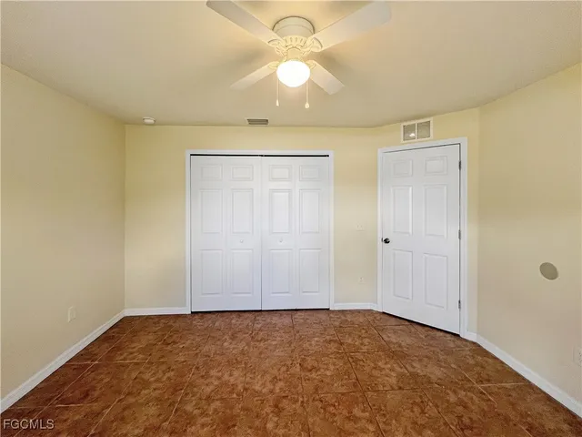 a view of an empty room and chandelier fan