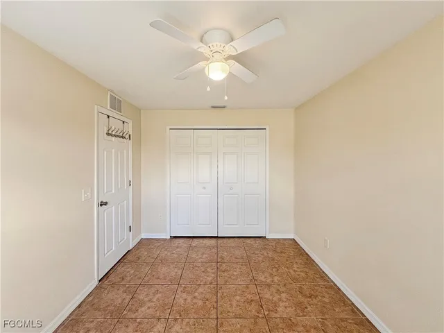 an empty room with a ceiling fan and carpet