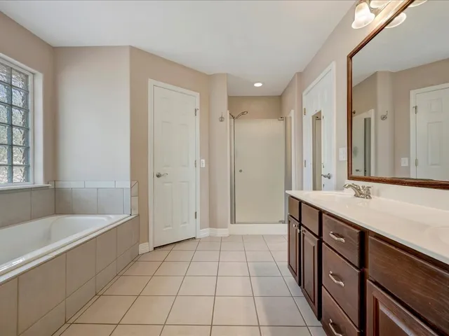 a spacious bathroom with a mirror a bathtub and a shower