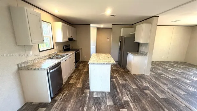 a kitchen with refrigerator a stove and white cabinets with wooden floor