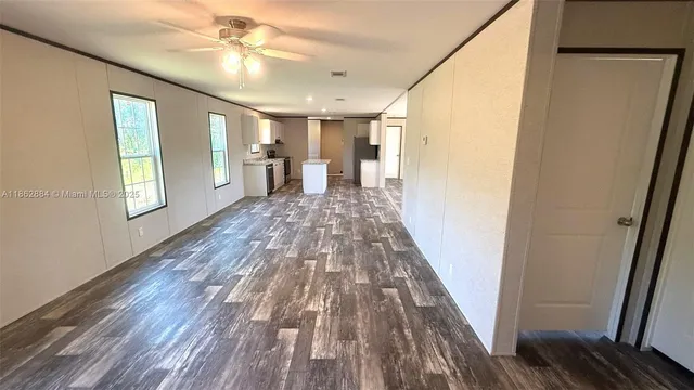 a view of a room with wooden floor fan and windows