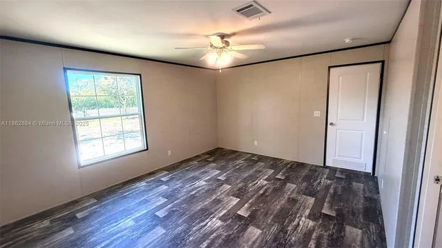 a view of an empty room with a window and wooden floor
