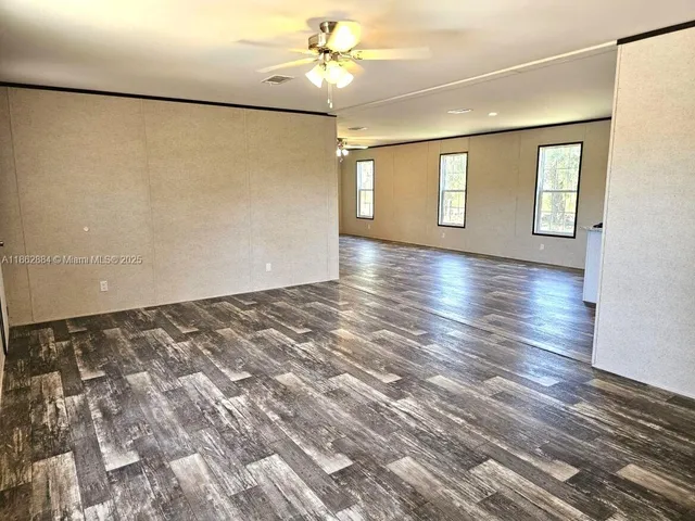 a view of an empty room with window and wooden floor