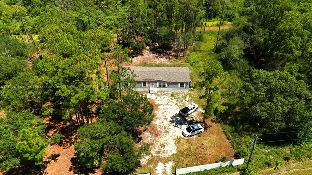 an aerial view of residential house with outdoor space and trees all around