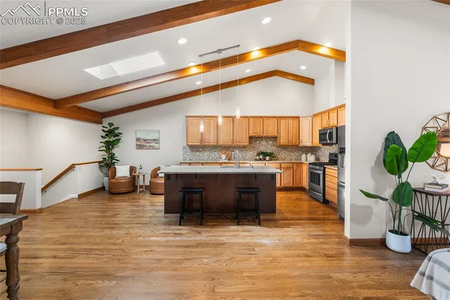 a kitchen with stainless steel appliances granite countertop a sink a stove and a wooden floors