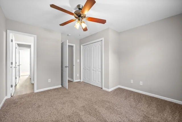 an empty room with closet and a chandelier fan