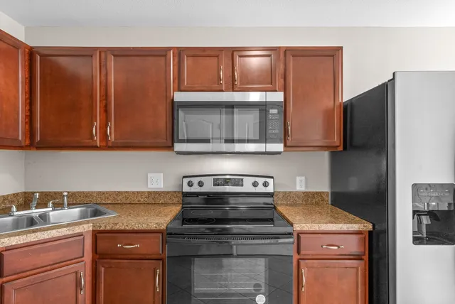 a kitchen with granite countertop a stove top oven microwave and cabinets