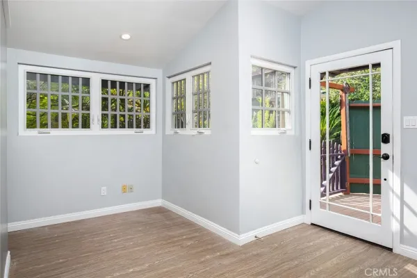a view of an empty room with wooden floor fireplace and a window