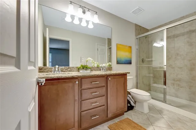 a bathroom with a granite countertop sink toilet and mirror