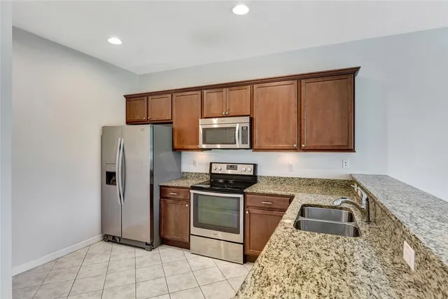 a kitchen with granite countertop a refrigerator stove and microwave