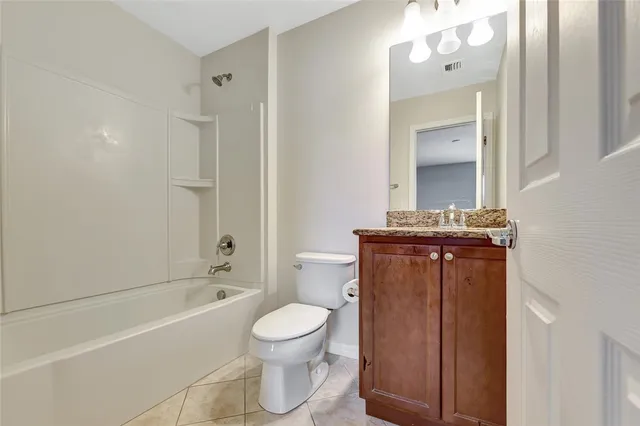 a bathroom with a granite countertop bathtub sink vanity mirror and toilet
