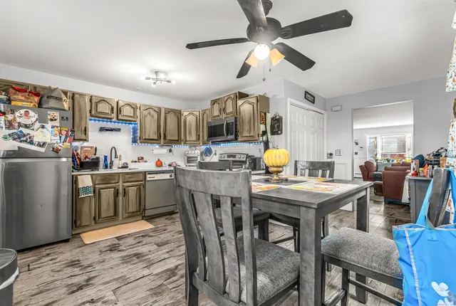 a kitchen with stainless steel appliances kitchen island granite countertop a table chairs and a refrigerator