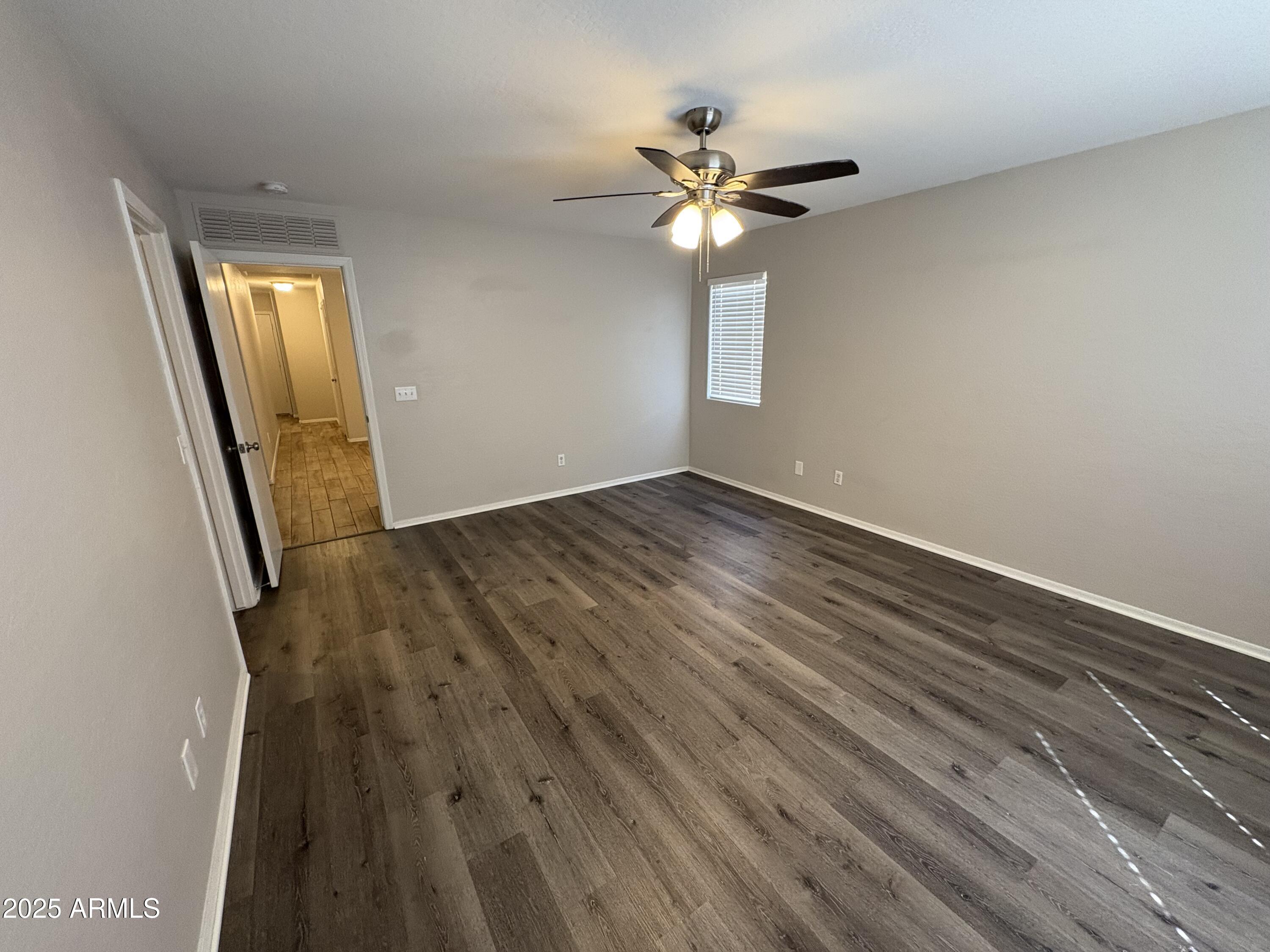 3323 South 80th Avenue Phoenix, AZ 85043 - Photo 5 of 7 an empty room with wooden floor fan and windows