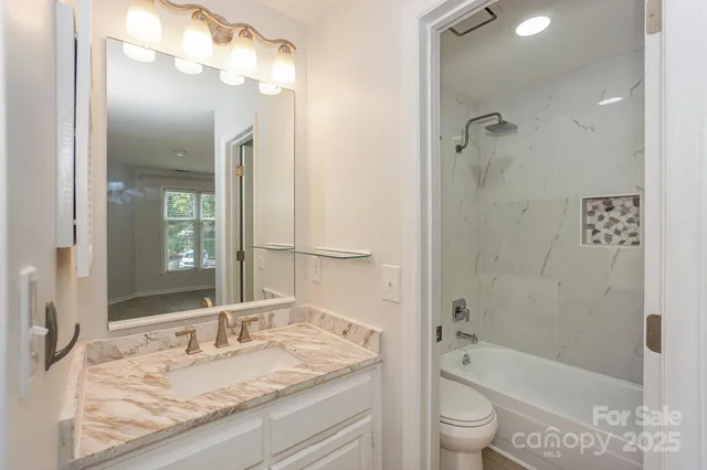 a bathroom with a granite countertop sink toilet mirror and shower