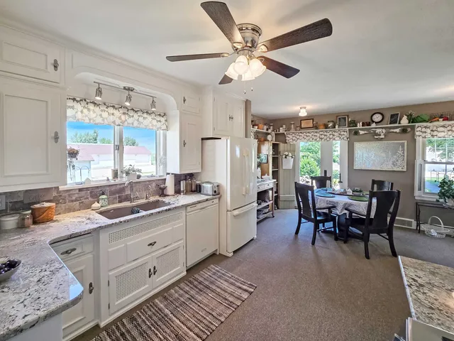 a kitchen with a dining table chairs sink and white cabinets
