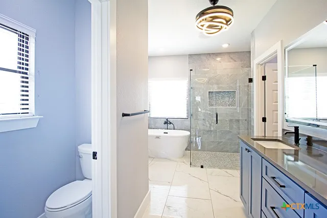 a bathroom with a granite countertop sink a toilet a mirror and shower