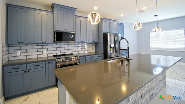 a kitchen with stainless steel appliances granite countertop a sink a stove counter space and cabinets