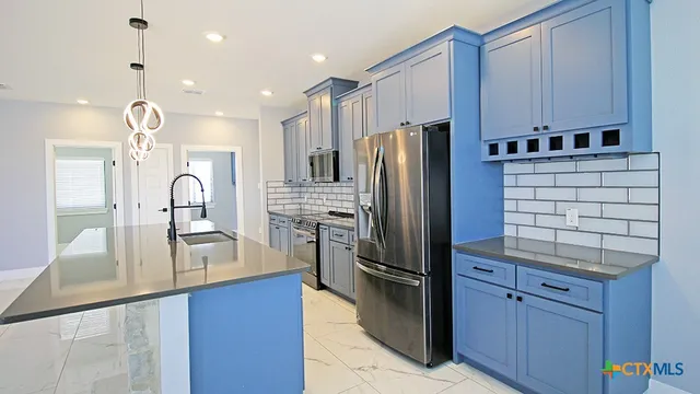 a kitchen with kitchen island granite countertop appliances cabinets and a sink