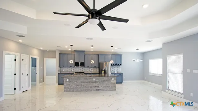 a large kitchen with stainless steel appliances kitchen island granite countertop a refrigerator and a stove top oven