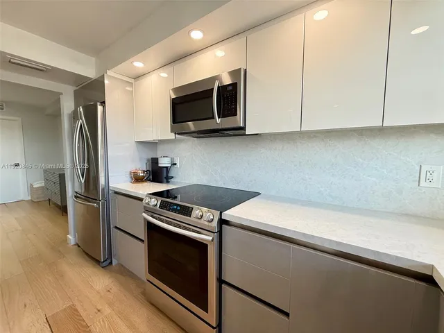 a kitchen with stainless steel appliances white cabinets and a stove top oven