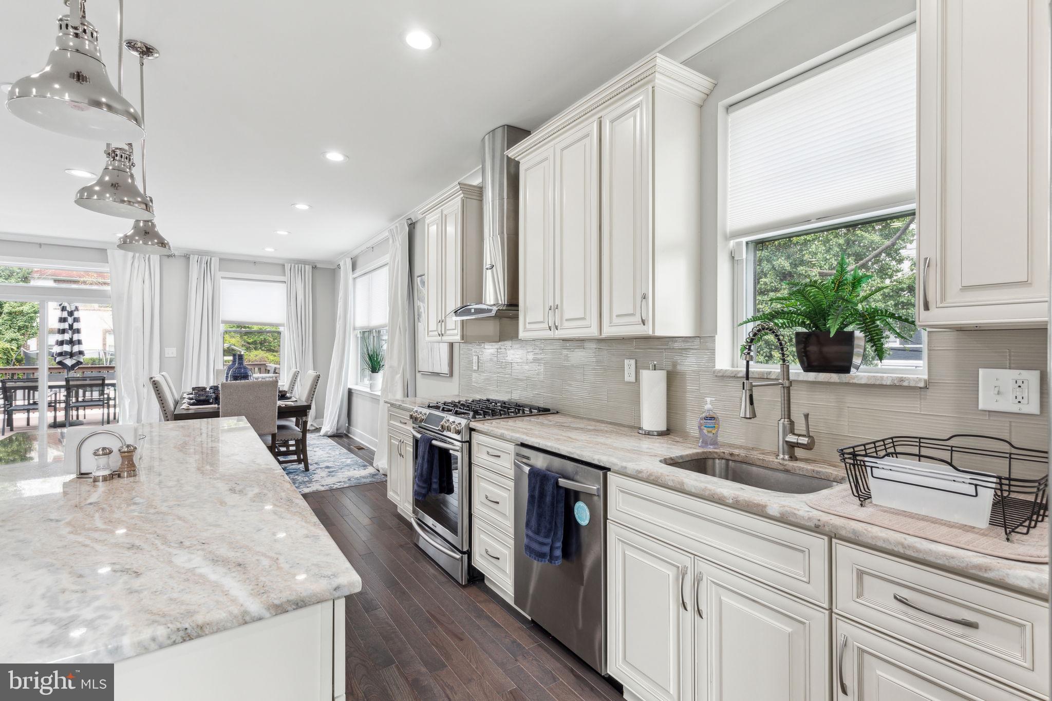 5301 Gainor Road Philadelphia, PA 19131 - Photo 8 of 51 a kitchen with stainless steel appliances granite countertop a stove a sink dishwasher and white cabinets with wooden floor
