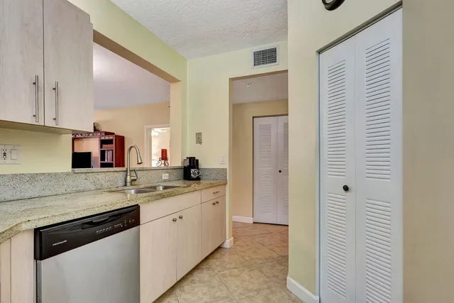 a kitchen with a sink dishwasher a stove and white cabinets