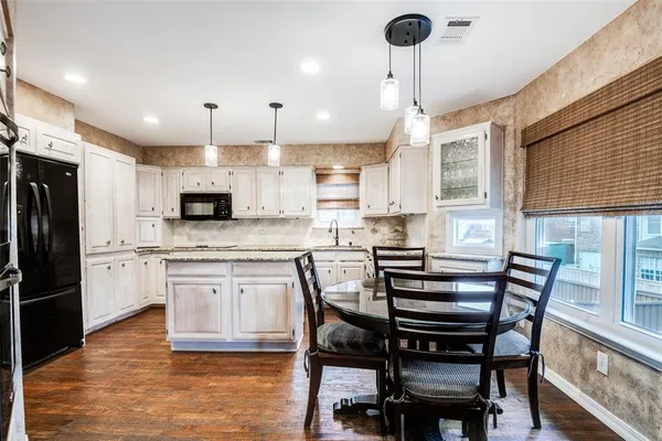a kitchen with kitchen island granite countertop a table chairs microwave and cabinets