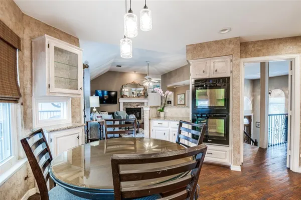 a dining room with wooden floor a chandelier a glass table and chairs