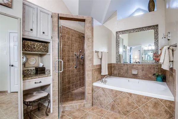 a bathroom with a tub a mirror and shower