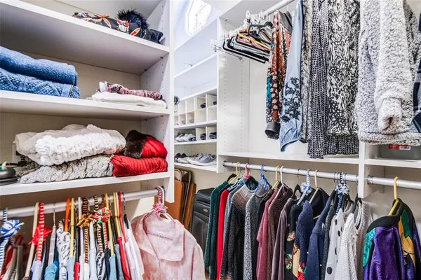 a view of walk in closet with clothes and shoes