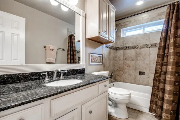 a bathroom with a granite countertop sink a toilet a mirror and shower