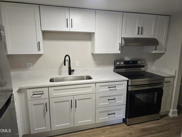 a kitchen with white cabinets and a stove with a sink
