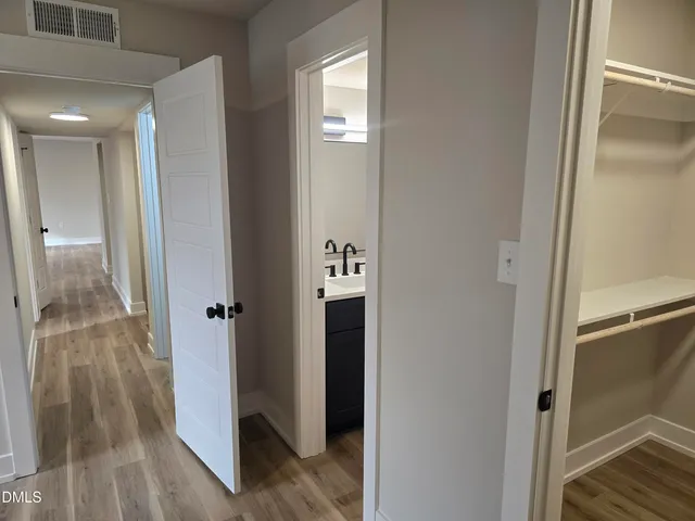 a view of a hallway with wooden floor and closet area