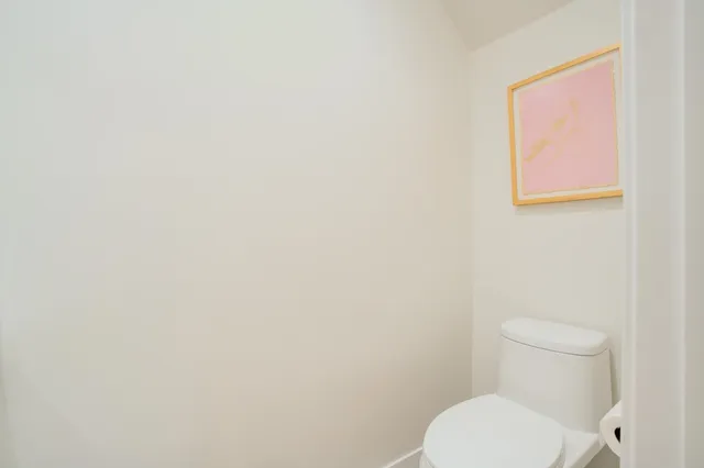 a white toilet sitting next to a white wall
