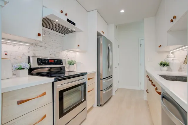 a kitchen with stainless steel appliances a stove a sink and a refrigerator