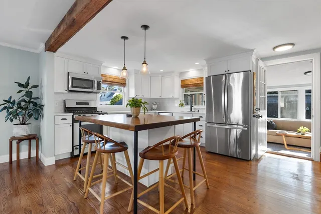 a kitchen with stainless steel appliances a refrigerator a stove a microwave a dining table and chairs with wooden floor