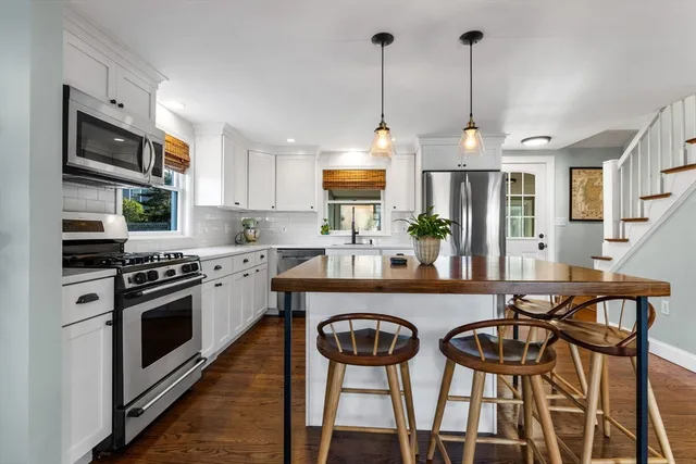 a kitchen with stainless steel appliances a stove a sink chairs and a refrigerator