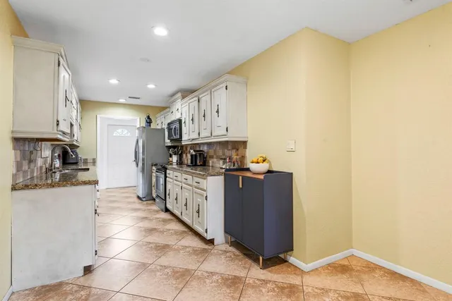 a large kitchen with stainless steel appliances granite countertop a refrigerator and a stove top oven