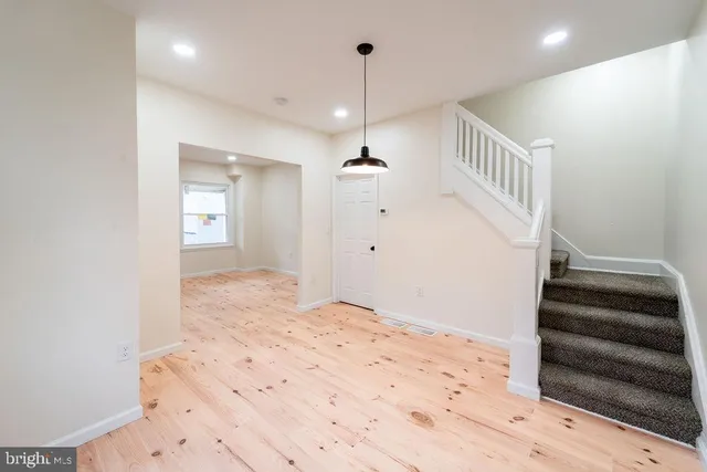 a view of an empty room with stairs and wooden floor